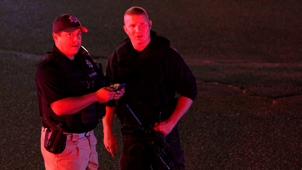   Police compare an image on a smartphone to a person they spotted in the crowd at the shooting scene  