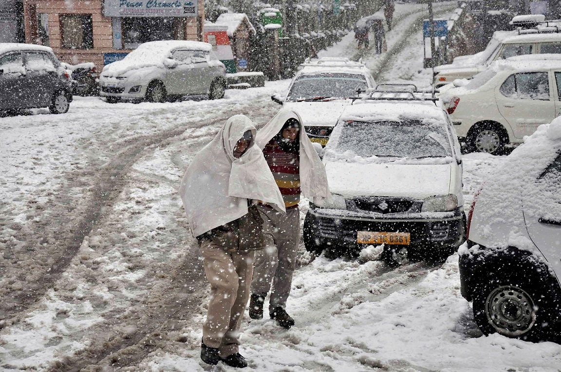   Dalhousie:  Two men try to cover themselves as it snows at Khajjiar Road in Dalhousie, Himachal Pradesh on Tuesday. PTI 