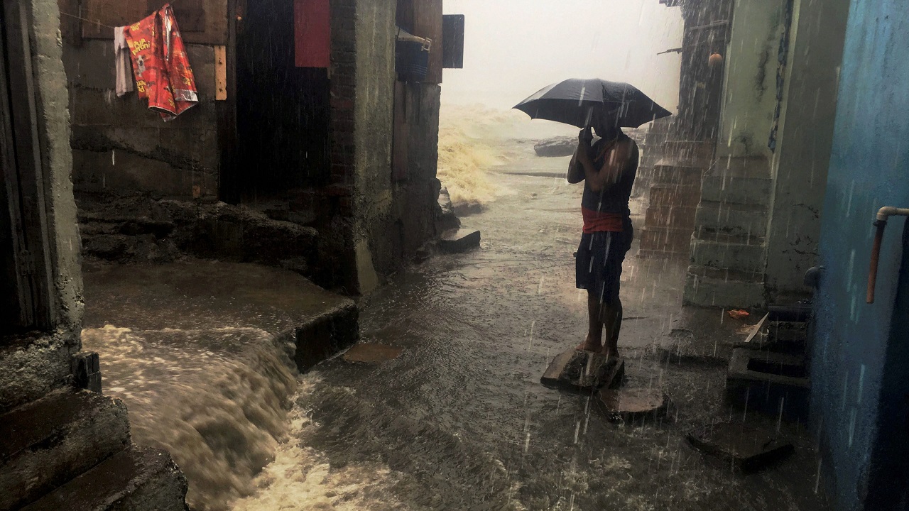   Mumbai: A man stand with an umbrella in a street amid heavy showers triggered by Cyclone Ockhi in Mumbai on Tuesday. (PTI Photo by Mitesh Bhuvad)  