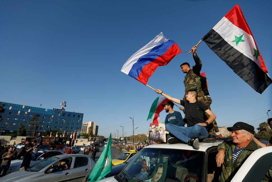  Syrians wave Russian and Syrian flags during a protest against US-led air strikes in Damascus. Image: Reuters 