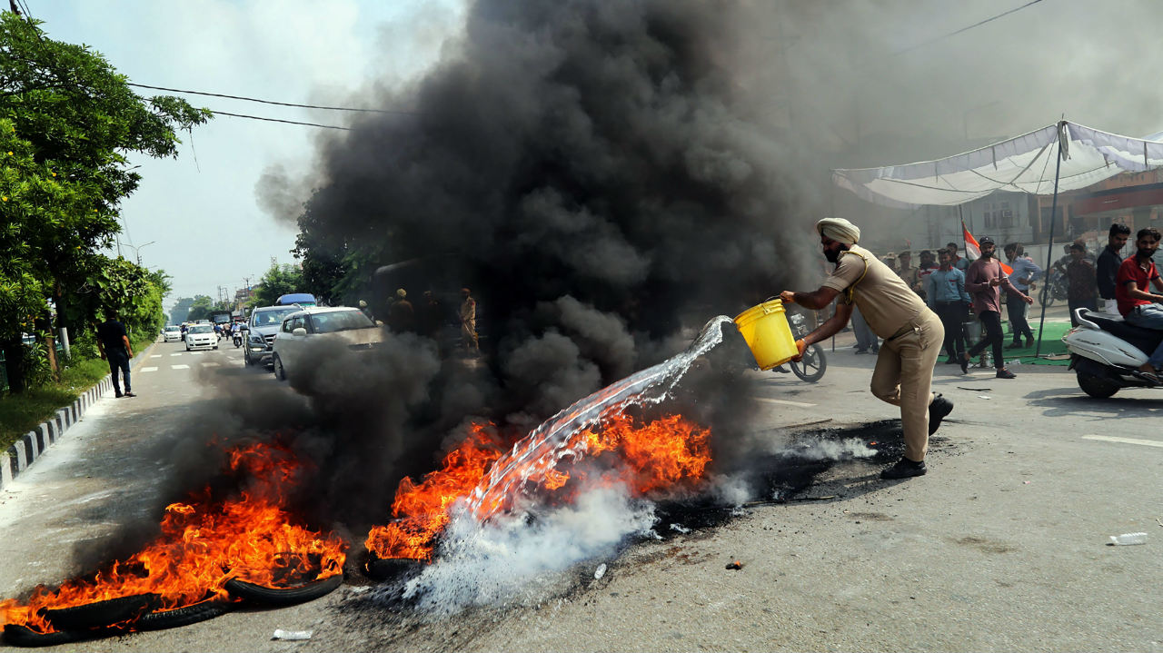   A policeman tries to douse a burning tyres during Bharat Bandh protest called by Congress and other parties against fuel price hike and depreciation of the rupee, in Jammu. (Image: PTI)  